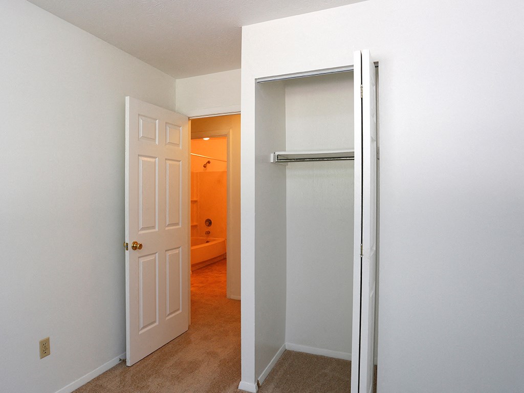 an empty bedroom with a closet and a door open to a bathroom