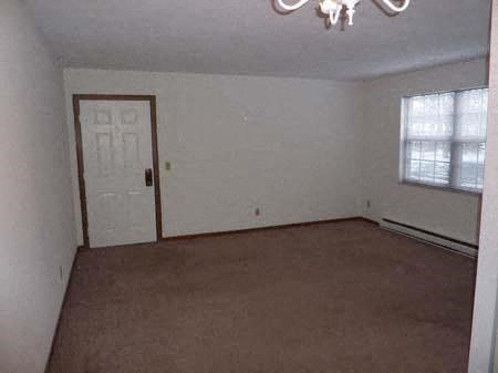 an empty living room with a white door and a window