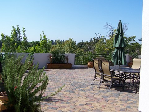 A patio with a table and chairs and a green umbrella.