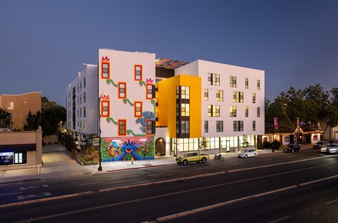 A building with a colorful mural on its side is illuminated at night.
