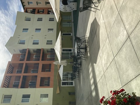 A building with a white wall and a green wall with a red building in the background.