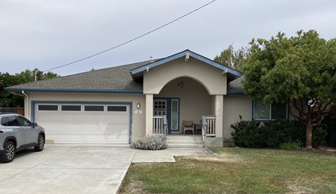 A house with a blue garage door and a grey car parked in front.