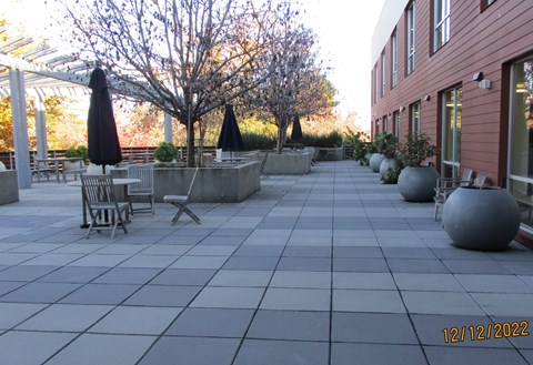 A patio with a table and chairs and umbrellas.