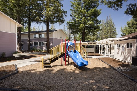 A playground with a blue slide and yellow railing.