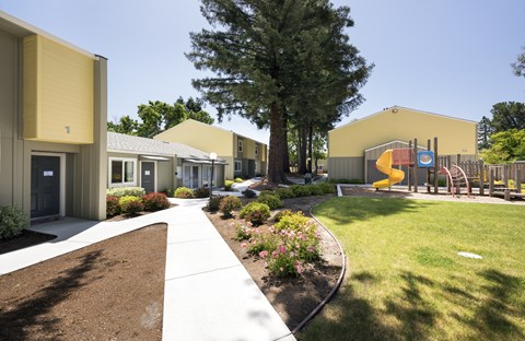 A playground with a slide and a yellow building in the background.