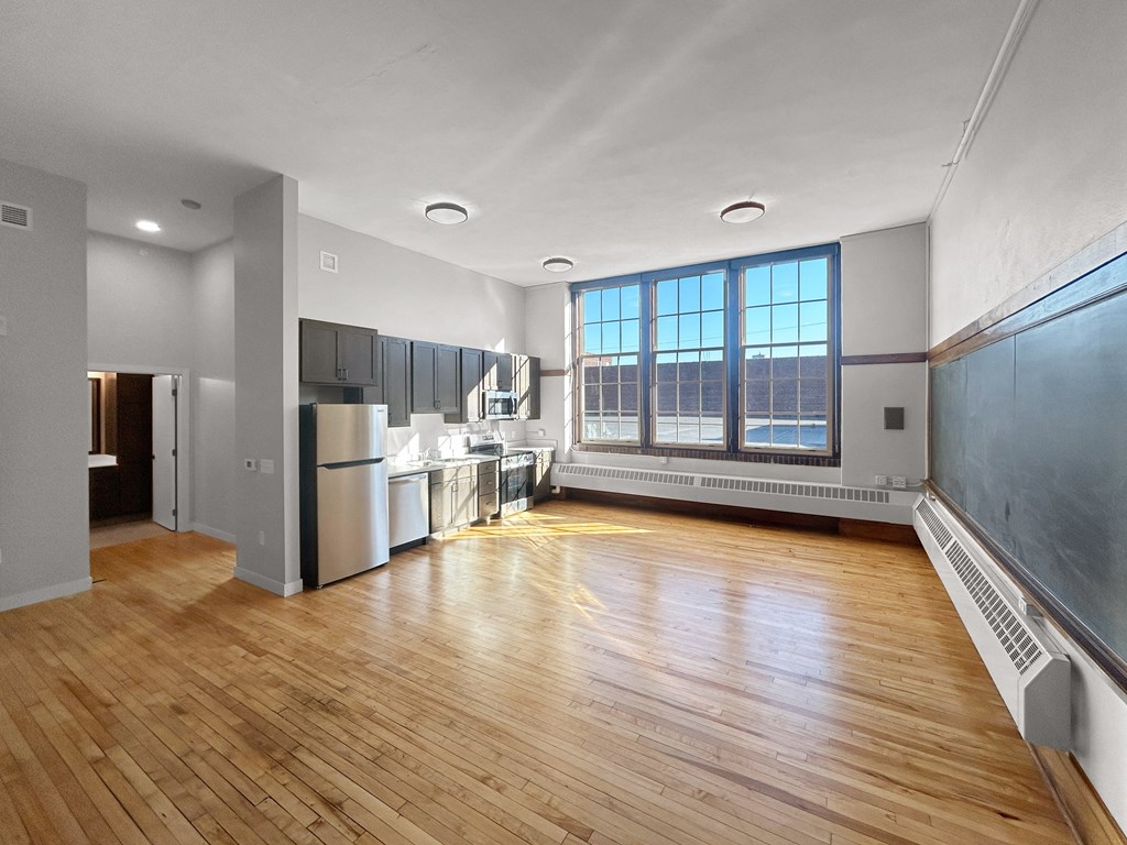 an empty living room and kitchen with wood floors and a window