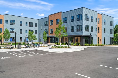 A parking lot in front of a multi-story building with a sign that says "The Shops at Hillcrest".