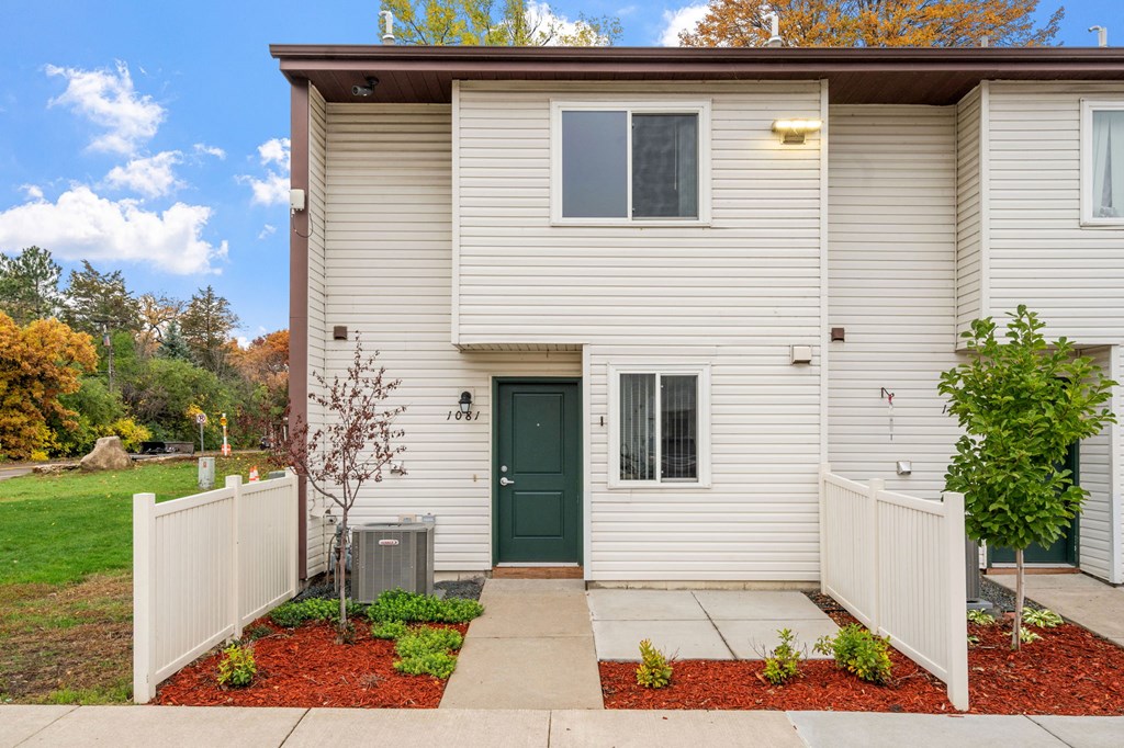 A house with a green door and a white fence.