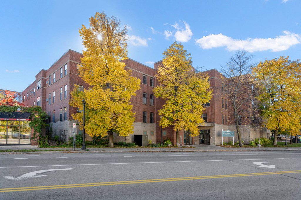 Exterior photo of Karinsplass Apartments with a blue sky overhead and bright, yellow trees