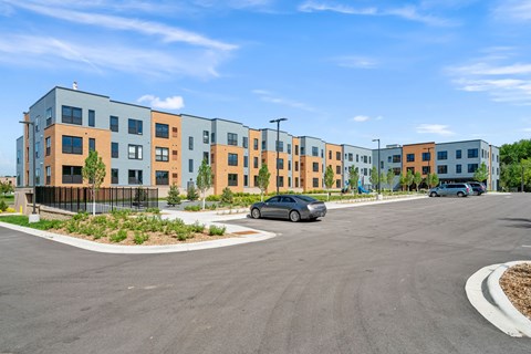 A modern apartment complex with a parking lot in front.
