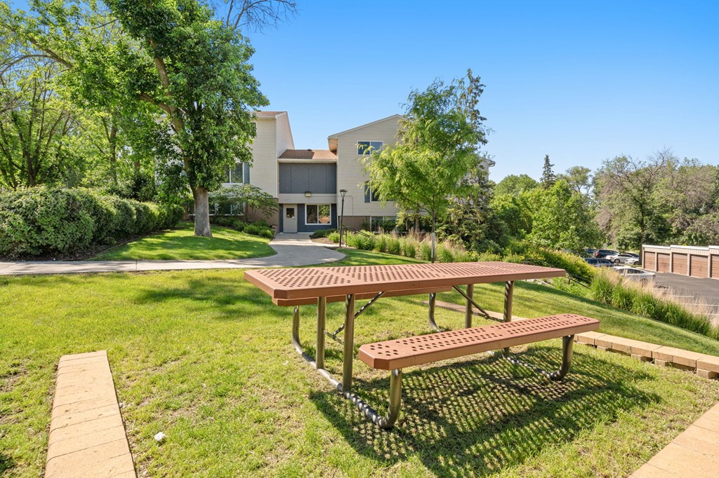 a picnic table in a park with a house in the background