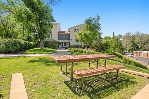 a picnic table in a park with a house in the background
