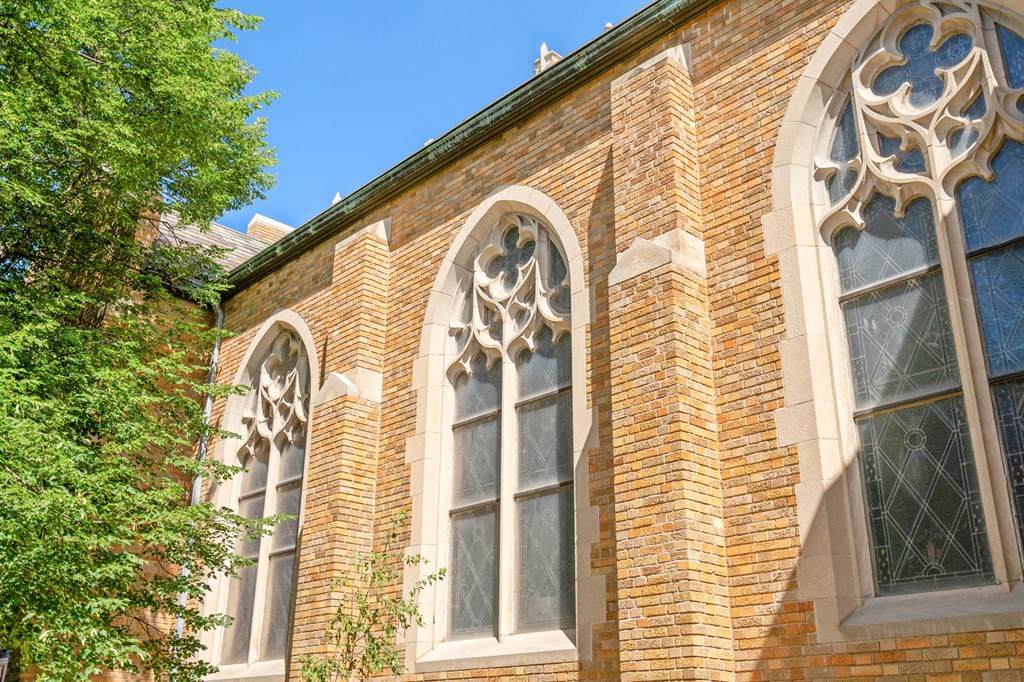 the side of a brick church with stained glass windows