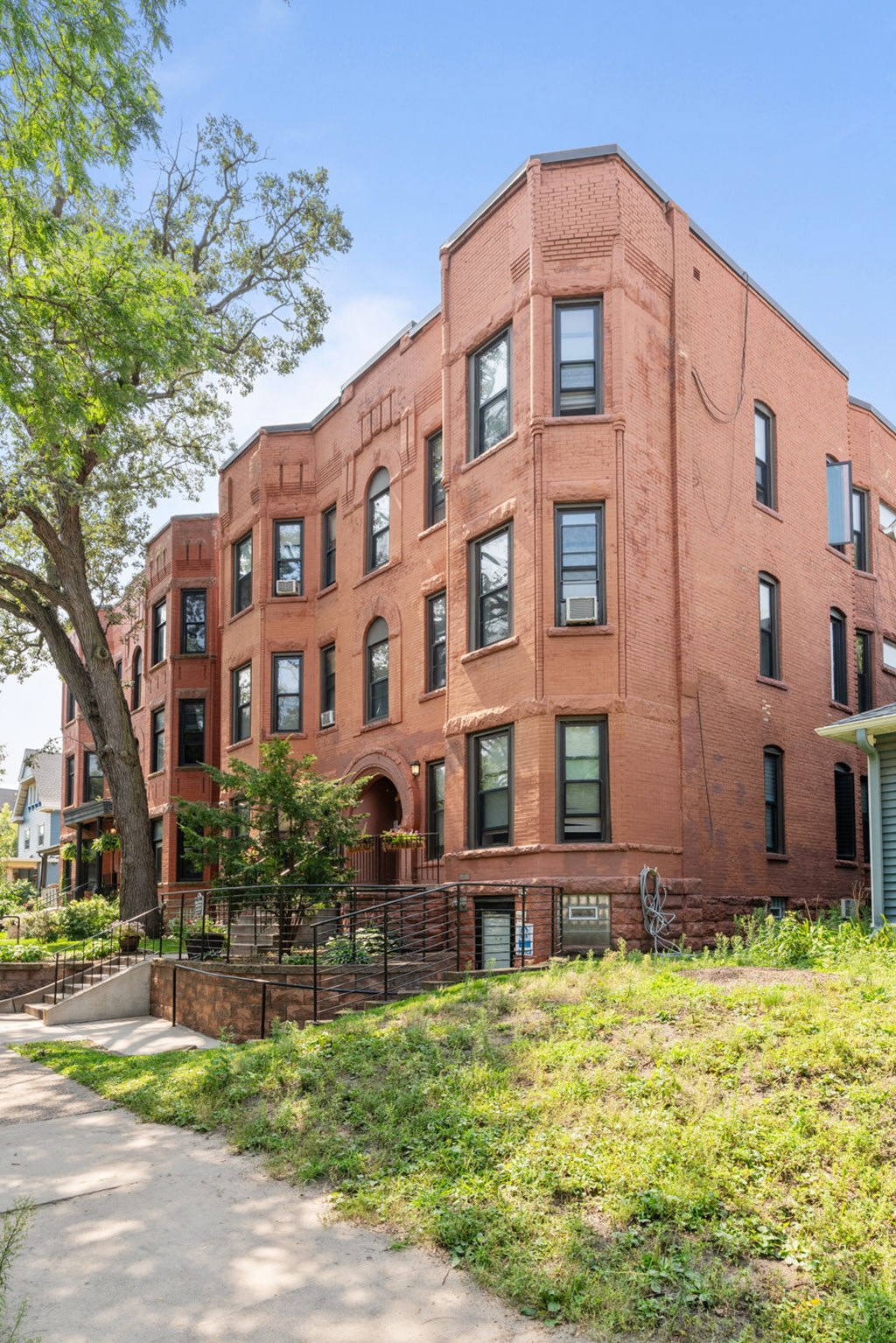 a red brick apartment building with a sidewalk and grass
