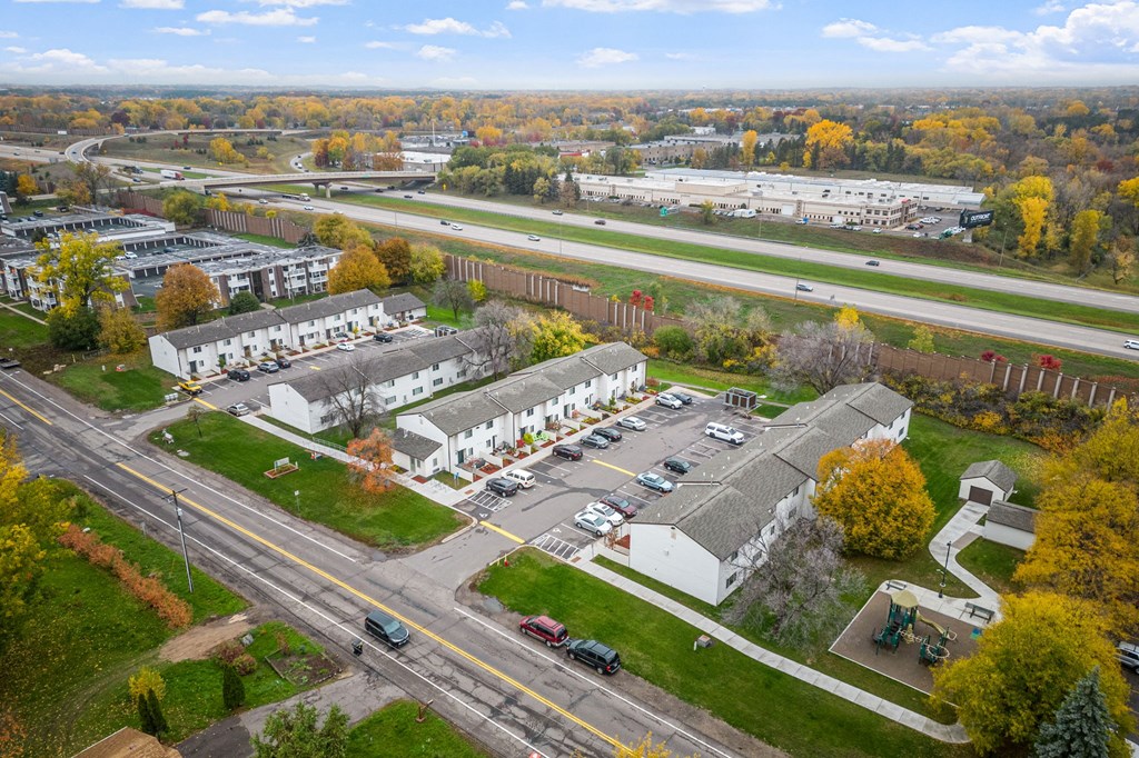 A road with cars and a white building with a grey roof.