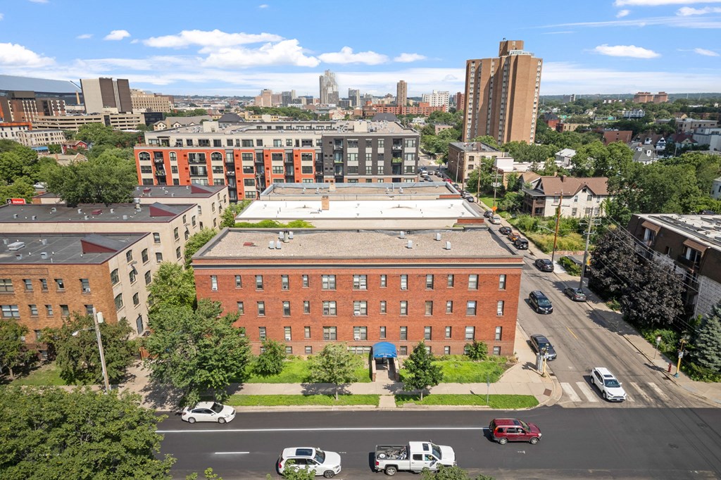 an aerial view of a red brick building with a white roof and a city skyline