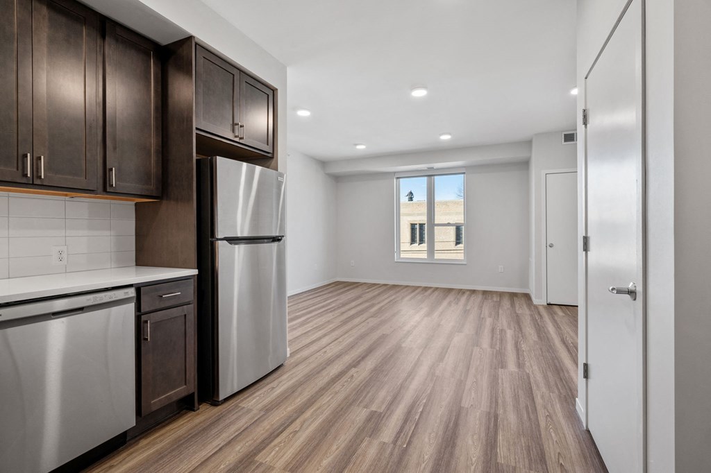 an empty kitchen and living room with a refrigerator and cabinets