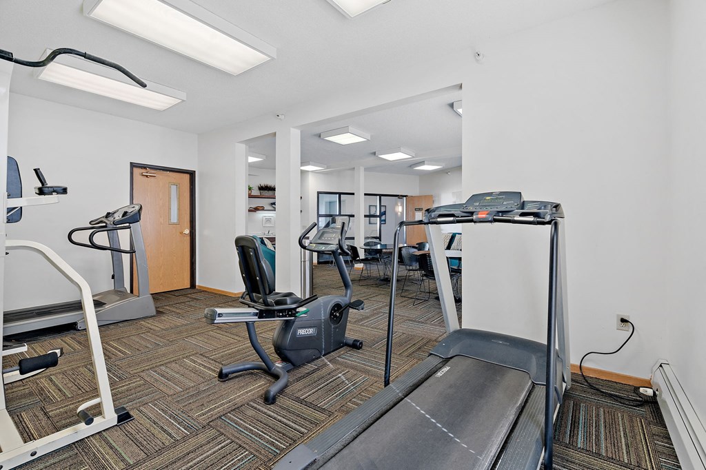 a gym with cardio equipment and weights on the floor