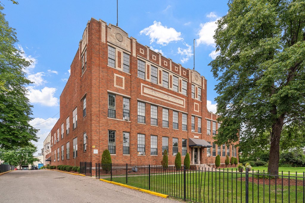 a large red brick building with a black wrought iron fence