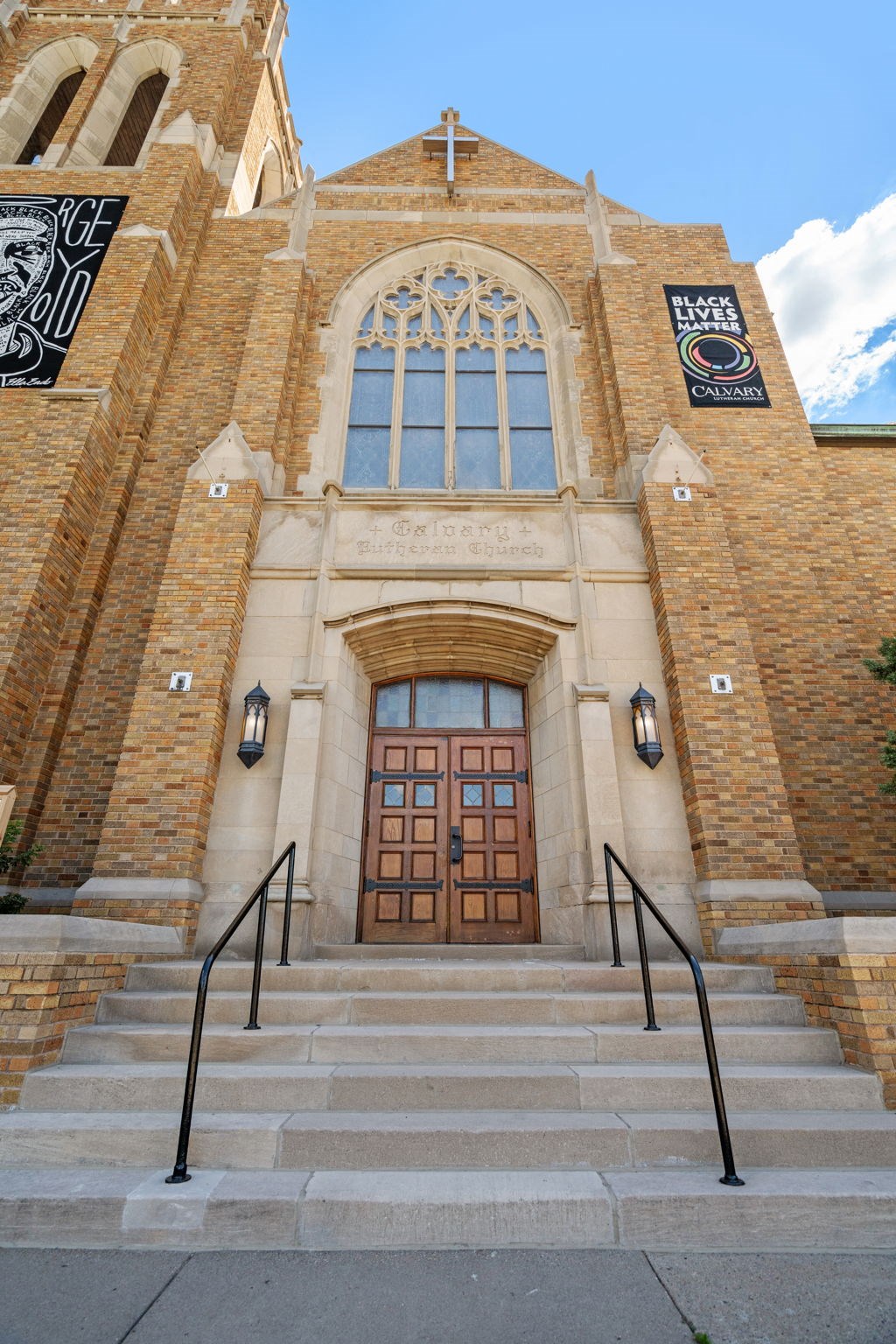 the front of a church with stairs and a brown door