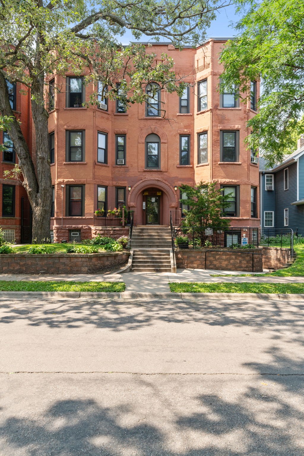 a brick building with stairs and trees in front of it