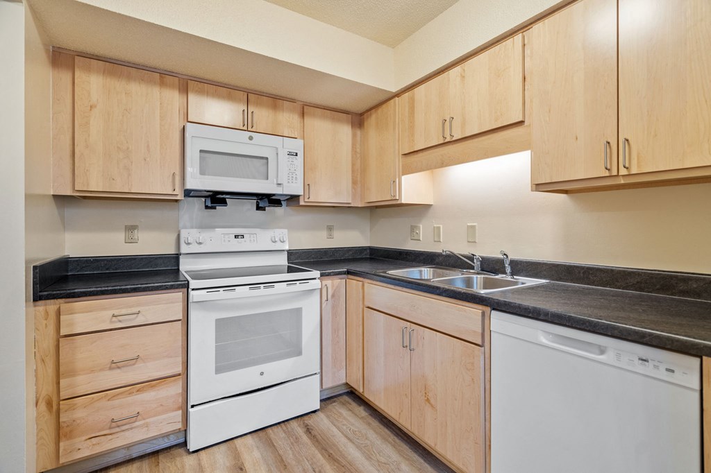 A kitchen with wooden cabinets and black countertops.