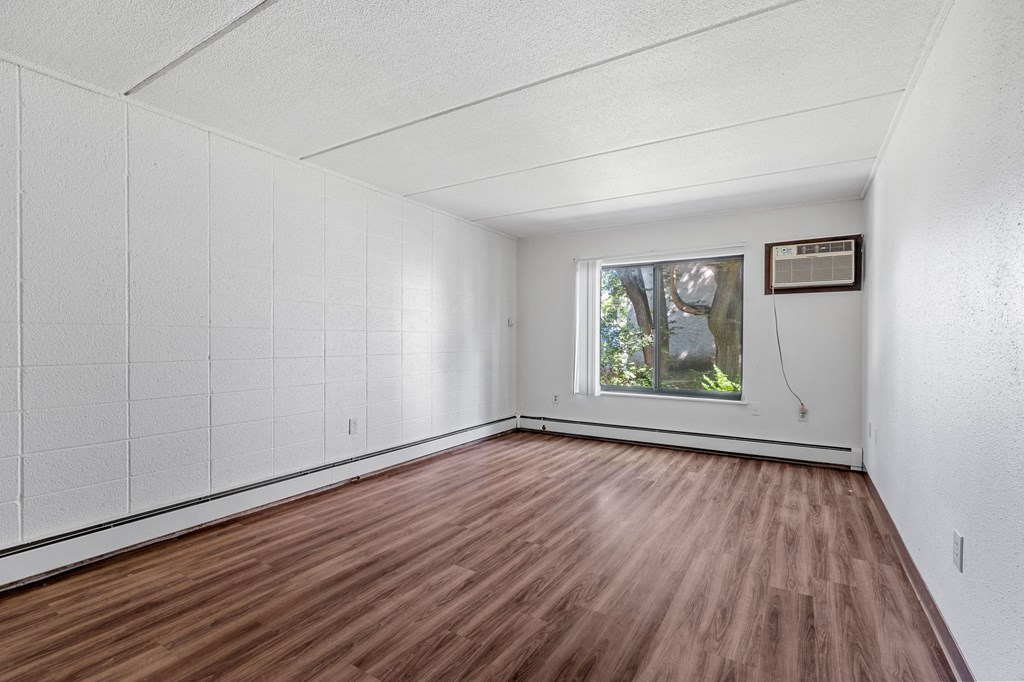 an empty living room with wood floors and a window