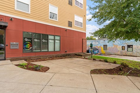 a sidewalk in front of a building with a mural on the side
