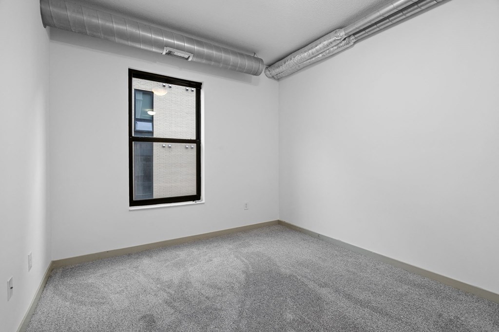 room with carpet and window in the corner of the room