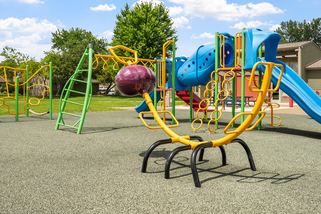 a playground with a blue and yellow swing set and a large ball