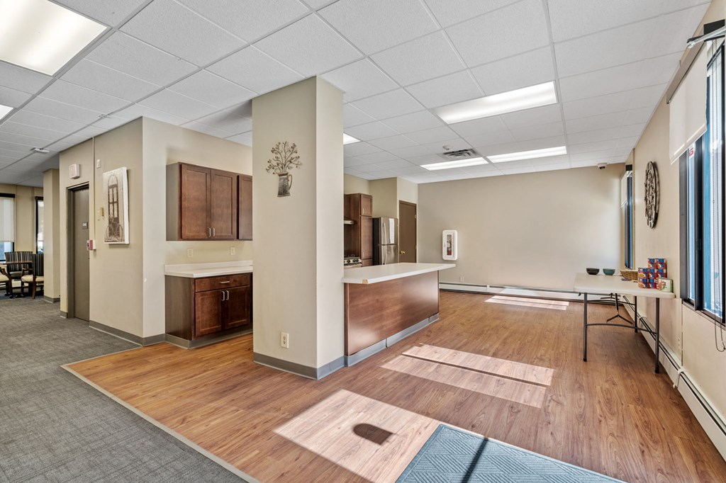 a community room with a wood floor and a table