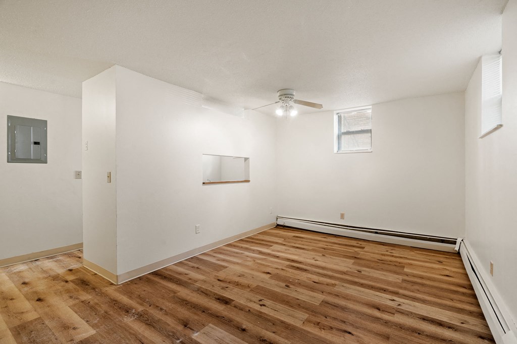 a living room with white walls and wood flooring and a ceiling fan