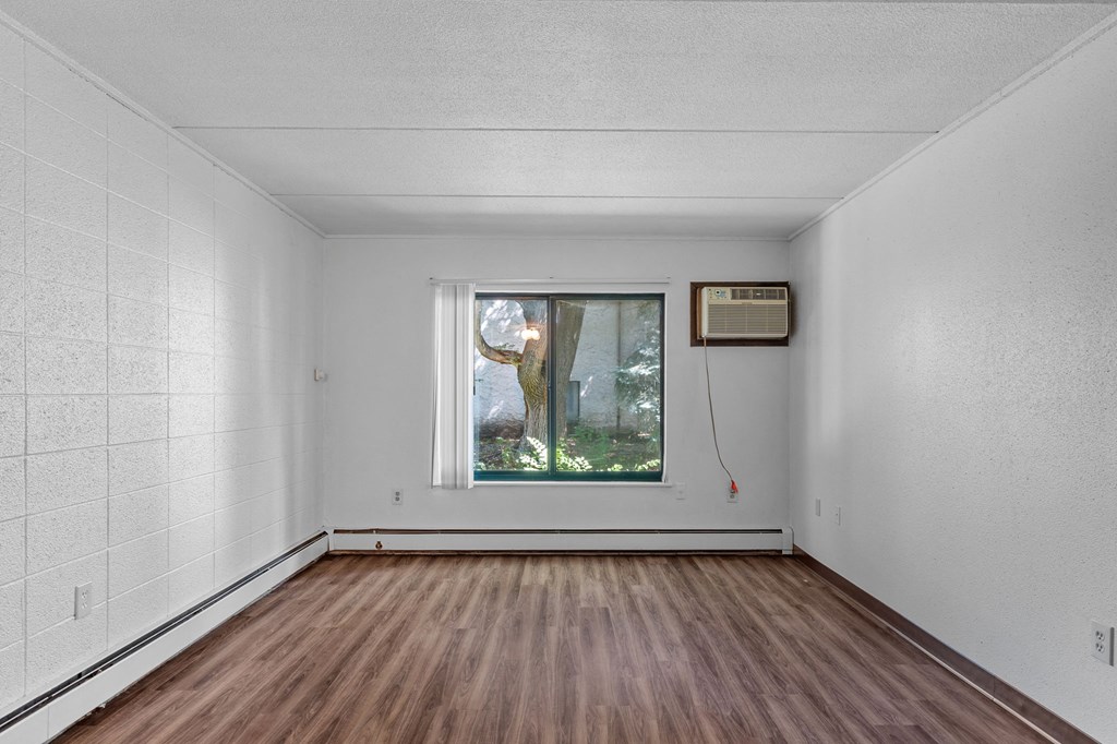 an empty room with a window and wooden floors
