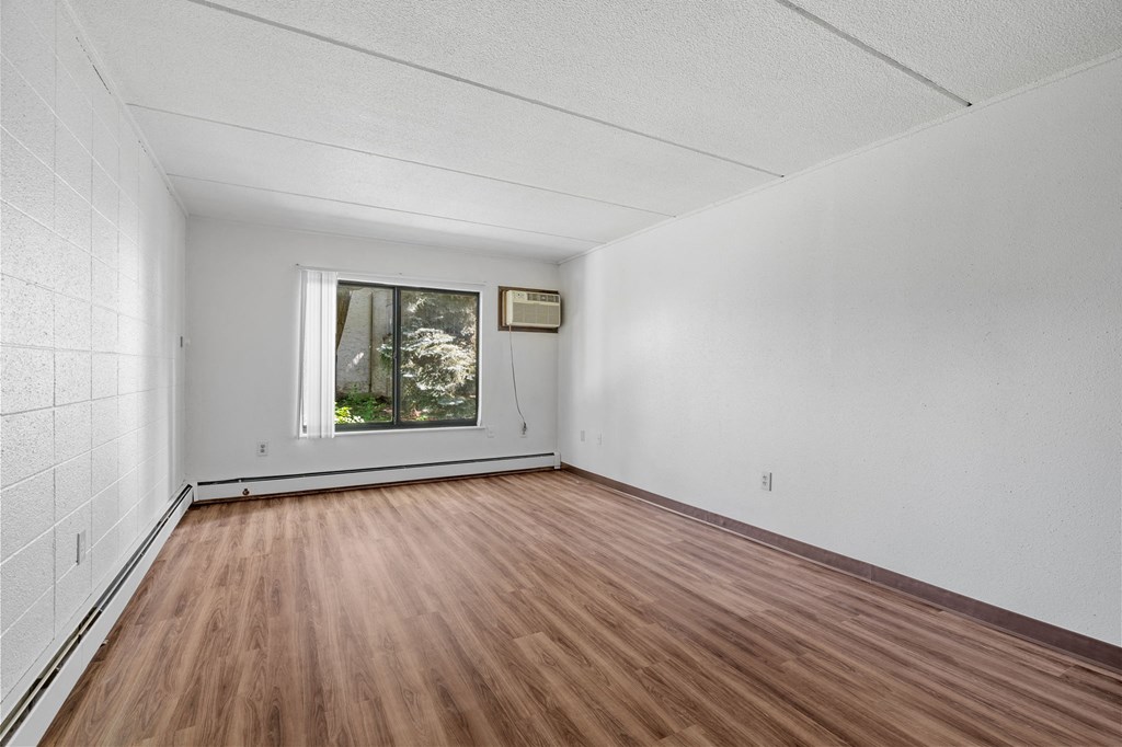 the living room of an empty house with wood floors and a window