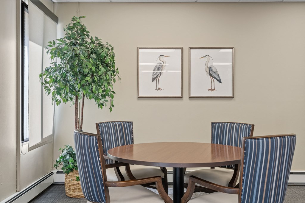 a dining room with a table and chairs and two pictures of birds on the wall