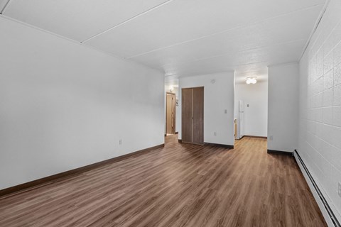 the living room and dining room of an apartment with wood floors and white walls