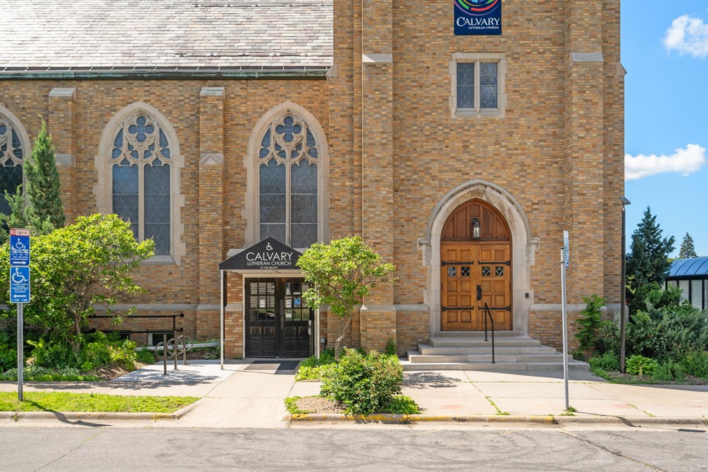 the front of a brick church with two large doors and a sign