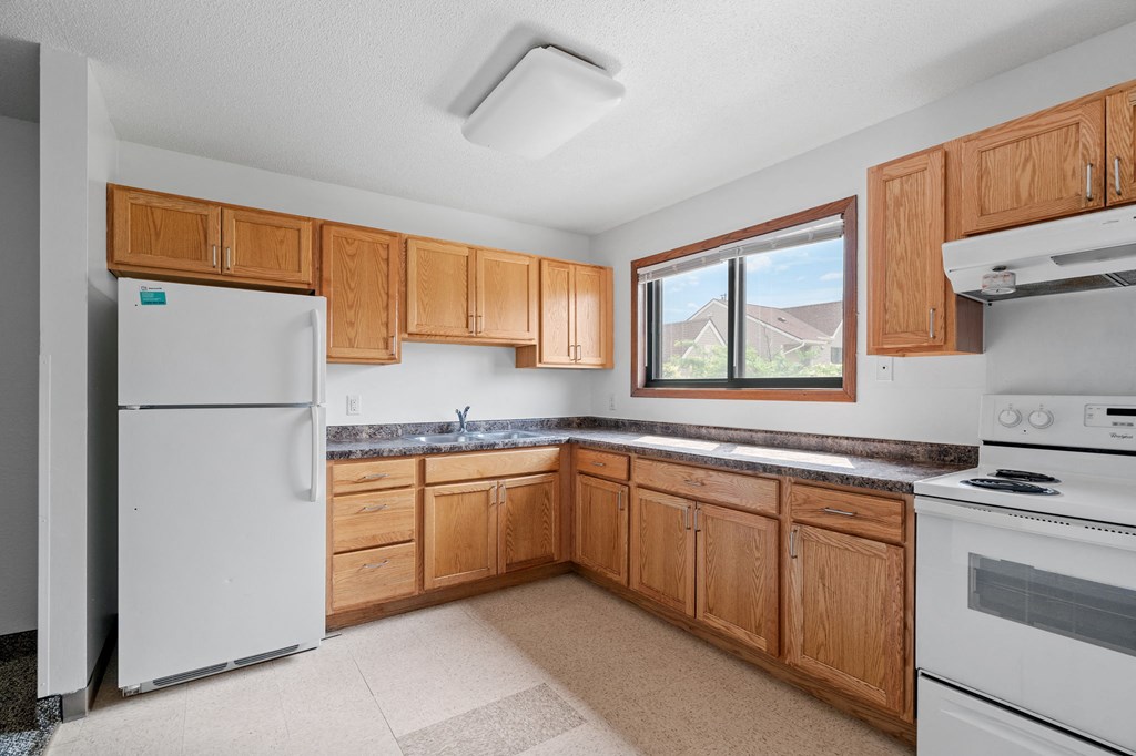 a kitchen with wooden cabinets and appliances and a window