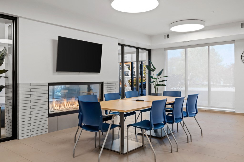 The community room with table, chairs, TV and a fireplace