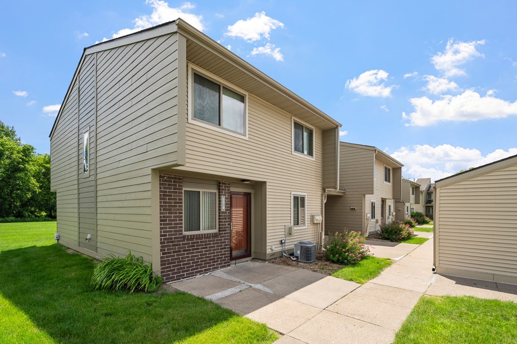 exterior view of two story apartment buildings with a sidewalk and grass