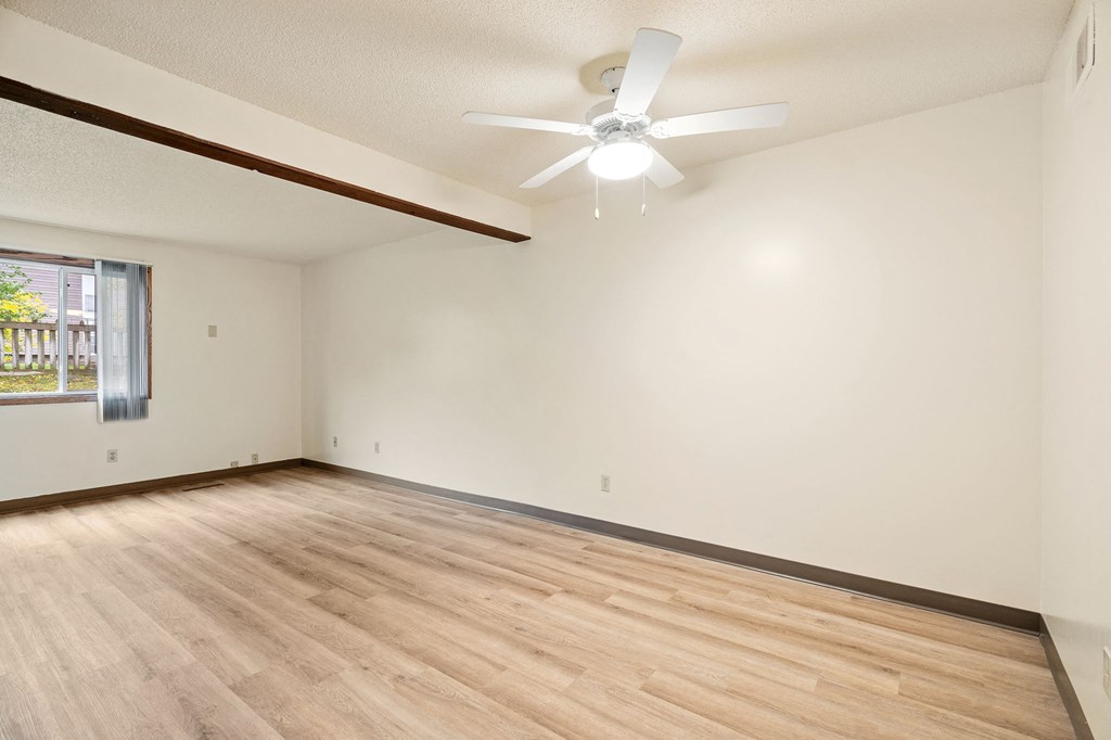 Empty room with a ceiling fan and wooden floor.