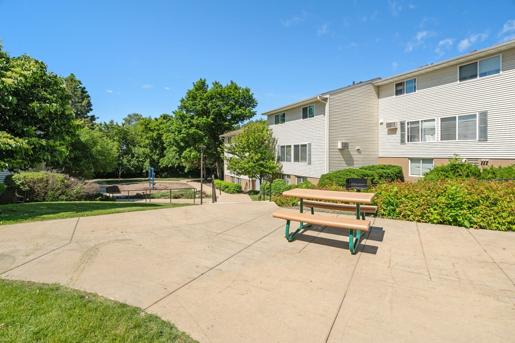 a picnic table on a sidewalk in front of an apartment building