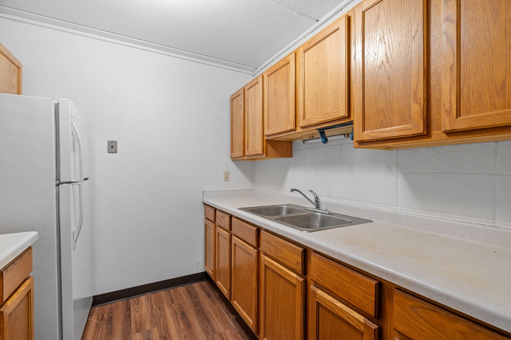 a kitchen with wooden cabinets and a sink and a refrigerator