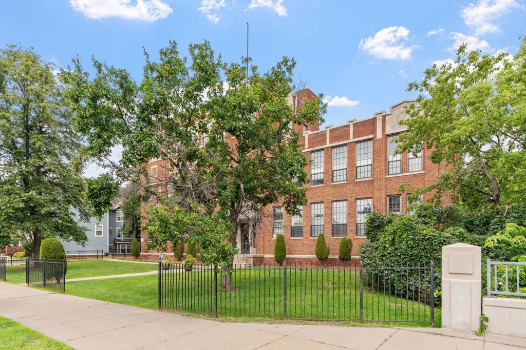 a large brick building with a lawn and trees in front of it