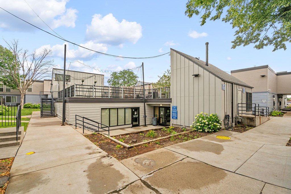 the exterior of a building with a sidewalk and a patio