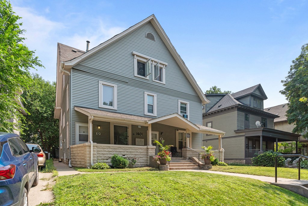 a blue house with a yard and cars parked in front of it