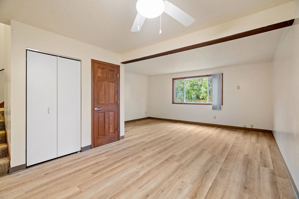 A room with a brown door and a window with a view of trees.