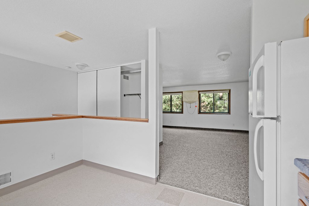 an empty kitchen with white walls and a white refrigerator