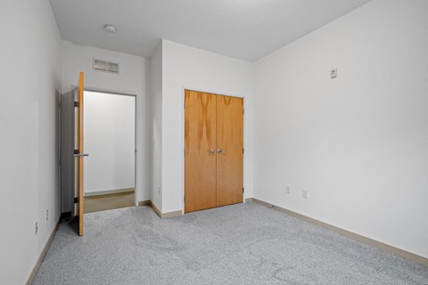 a bedroom with carpet and a door to a closet