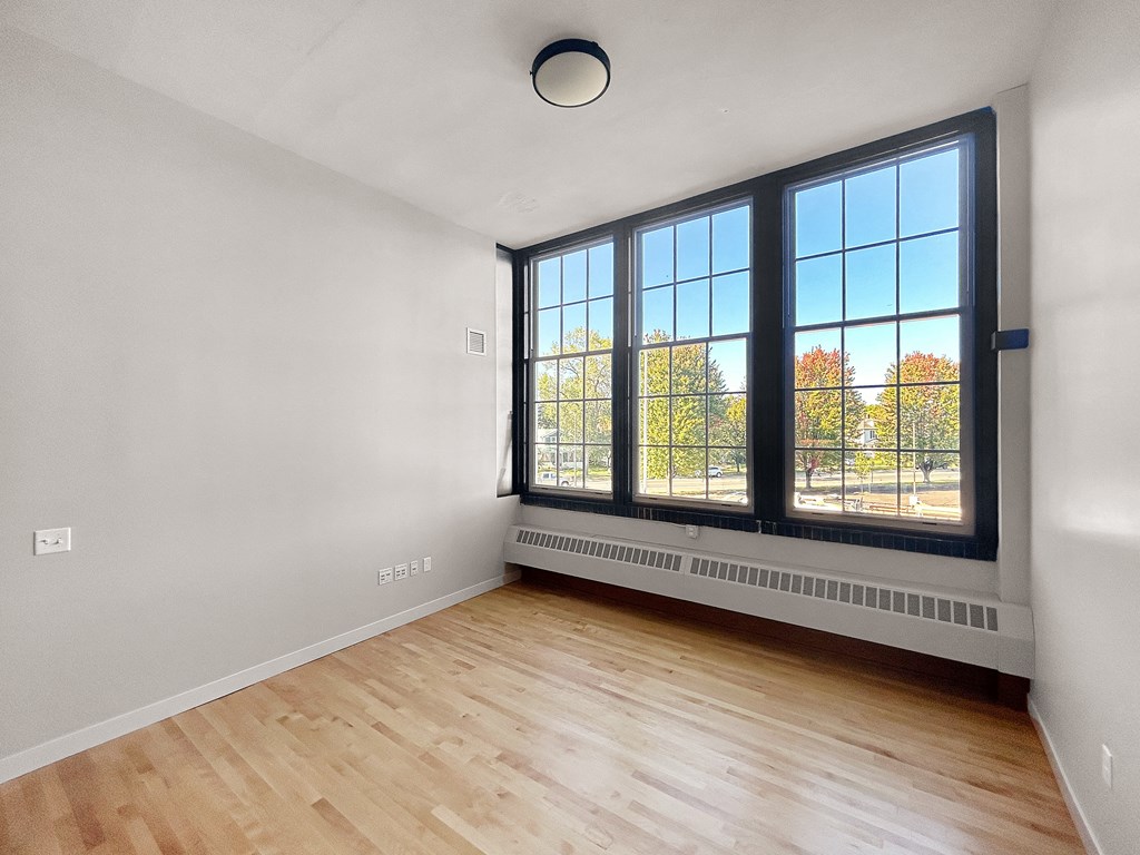 an empty living room with a large window and wood flooring